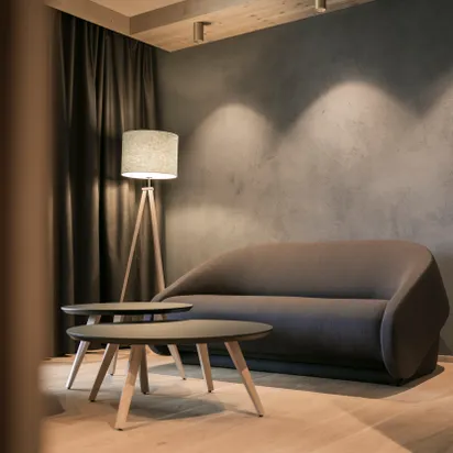 Modernes Wohnzimmer mit grauem Sofa, runden Couchtischen und Stehlampe auf Holzboden